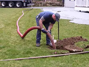 Septic pumping technician servicing a residential septic tank with a vacuum hose in Memphis, TN