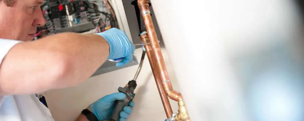 Water heater repair technician testing copper pipe connections and controls in Memphis, TN