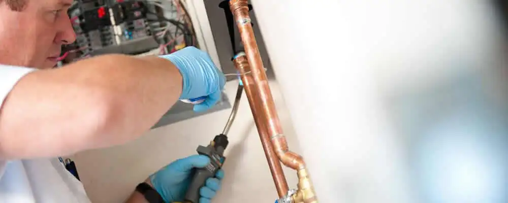 Water heater repair technician testing copper pipe connections and controls in Memphis, TN